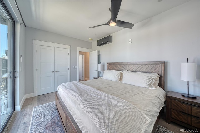 bedroom featuring baseboards, a wall unit AC, ceiling fan, wood finished floors, and a closet