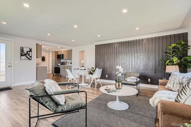 5555 Julian St, Denver, CO 80221 - living room featuring arched walkways, light wood-style flooring, recessed lighting, baseboards, and an accent wall