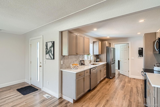 5555 Julian St, Denver, CO 80221 - kitchen featuring appliances with stainless steel finishes, a sink, light wood-style floors, light countertops, and a textured ceiling