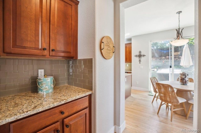 3102 Fox Sedge Pl, Highlands Ranch, CO 80126 - kitchen with tasteful backsplash, light wood-style floors, light stone countertops, baseboards, and brown cabinetry
