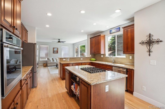 3102 Fox Sedge Pl, Highlands Ranch, CO 80126 - kitchen with appliances with stainless steel finishes, a peninsula, open floor plan, light wood finished floors, and a kitchen island