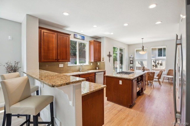 3102 Fox Sedge Pl, Highlands Ranch, CO 80126 - kitchen with light wood-type flooring, a peninsula, decorative backsplash, a kitchen breakfast bar, and a sink