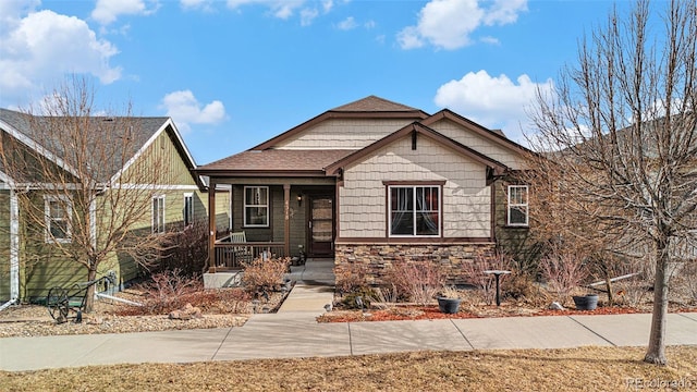 view of front of home featuring covered porch and stone siding