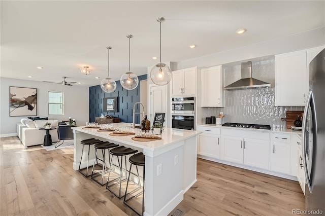 15290 W 69th Pl, Arvada, CO 80007 - kitchen with wall chimney exhaust hood, appliances with stainless steel finishes, open floor plan, a kitchen bar, and backsplash