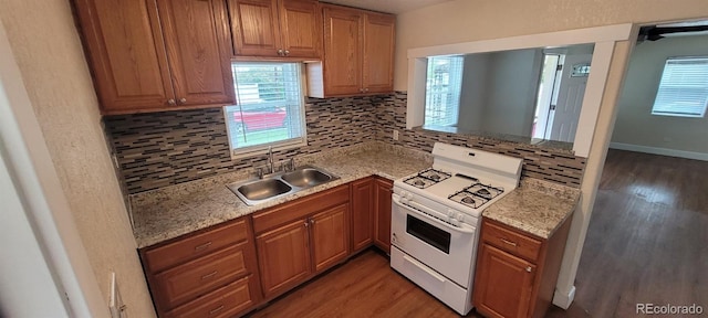2880 W 91st Pl, Denver, CO 80260 - kitchen with white gas range oven, a sink, backsplash, and light wood-type flooring