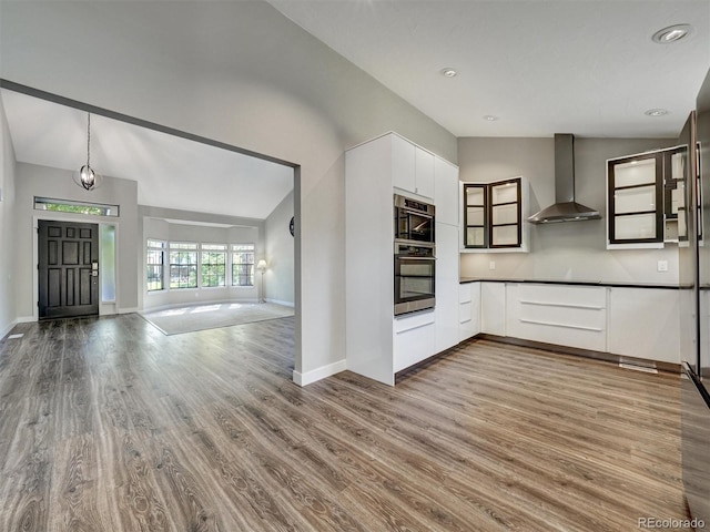 15915 E Mercer Cir, Aurora, CO 80013 - kitchen with wall chimney range hood, oven, vaulted ceiling, wood finished floors, and white cabinets