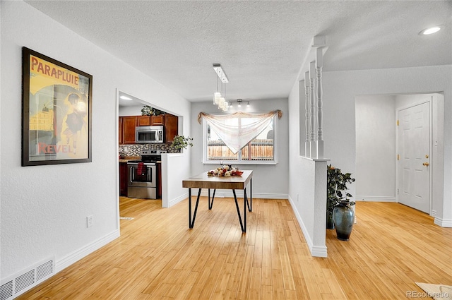 7819 Tejon St, Denver, CO 80221 - dining area featuring light wood finished floors, a textured ceiling, and a chandelier