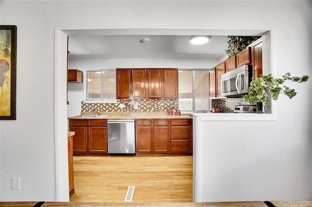 7819 Tejon St, Denver, CO 80221 - kitchen with appliances with stainless steel finishes, backsplash, light wood-type flooring, a textured wall, and brown cabinets