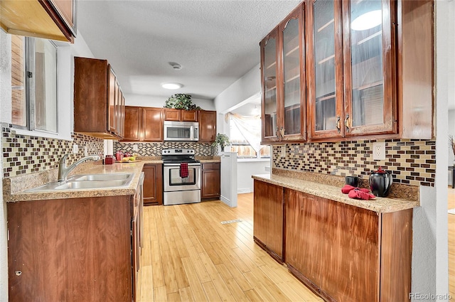 7819 Tejon St, Denver, CO 80221 - kitchen featuring appliances with stainless steel finishes, light wood-style floors, backsplash, light countertops, and a textured ceiling