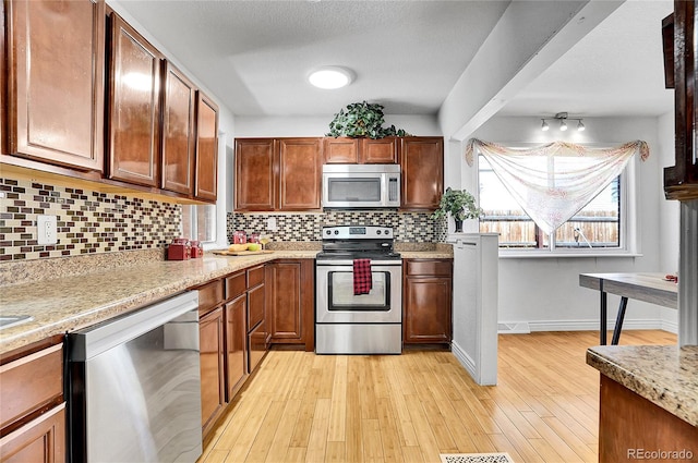7819 Tejon St, Denver, CO 80221 - kitchen with appliances with stainless steel finishes, backsplash, light wood-style flooring, and brown cabinetry