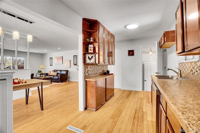 7819 Tejon St, Denver, CO 80221 - kitchen featuring backsplash, pendant lighting, brown cabinetry, light wood-style flooring, and open floor plan