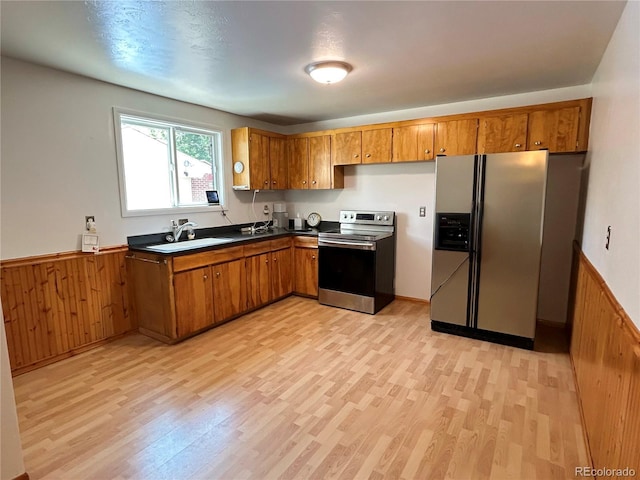 660 Wolff St, Denver, CO 80204 - kitchen featuring appliances with stainless steel finishes, a sink, brown cabinets, light wood finished floors, and a wainscoted wall