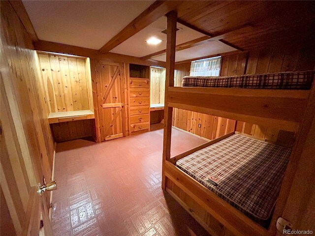 660 Wolff St, Denver, CO 80204 - bedroom featuring wooden walls, beamed ceiling, and tile patterned floors