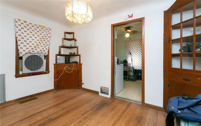 interior space featuring washer / clothes dryer, hardwood / wood-style flooring, ceiling fan with notable chandelier, and heating unit