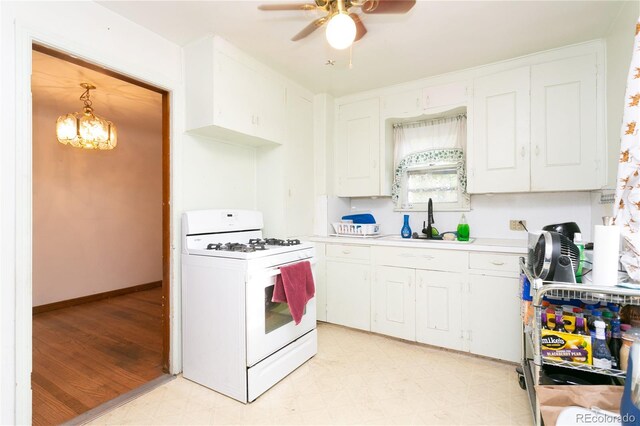 kitchen with white cabinets, ceiling fan with notable chandelier, light wood-type flooring, white range with gas cooktop, and sink