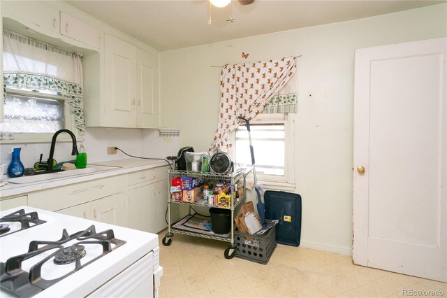 kitchen featuring white stove, sink, and white cabinets