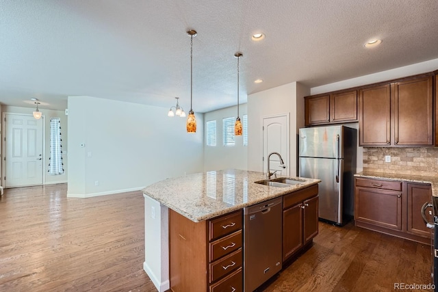 kitchen featuring a center island with sink, appliances with stainless steel finishes, dark hardwood / wood-style flooring, sink, and backsplash