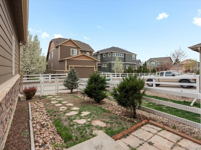 view of yard with fence, a residential view, and a garage