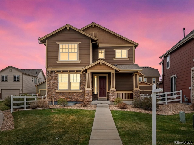 view of front of property featuring fence, a lawn, stone siding, and a garage