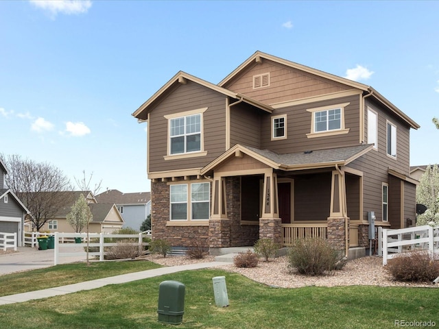 craftsman inspired home with a porch, stone siding, a front yard, and fence