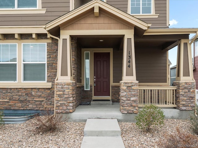 entrance to property featuring a porch and stone siding