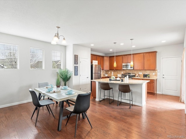 dining space with baseboards, wood finished floors, recessed lighting, and a notable chandelier