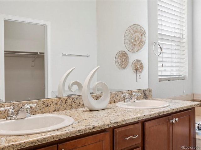 full bathroom with double vanity, a spacious closet, and a sink