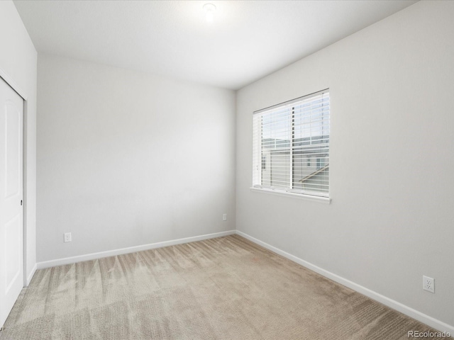 carpeted spare room featuring baseboards