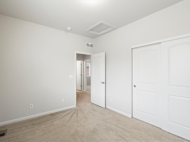 unfurnished bedroom featuring attic access, visible vents, baseboards, light colored carpet, and a closet