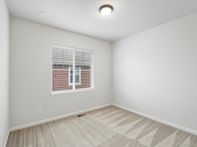 spare room with baseboards, visible vents, and carpet