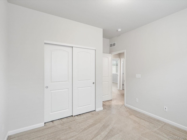 unfurnished bedroom with a closet, visible vents, carpet flooring, and baseboards