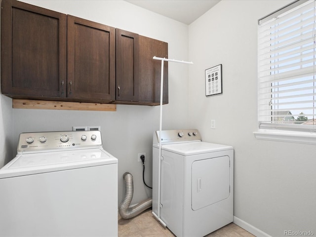 clothes washing area featuring cabinet space, baseboards, light tile patterned flooring, and washer and clothes dryer