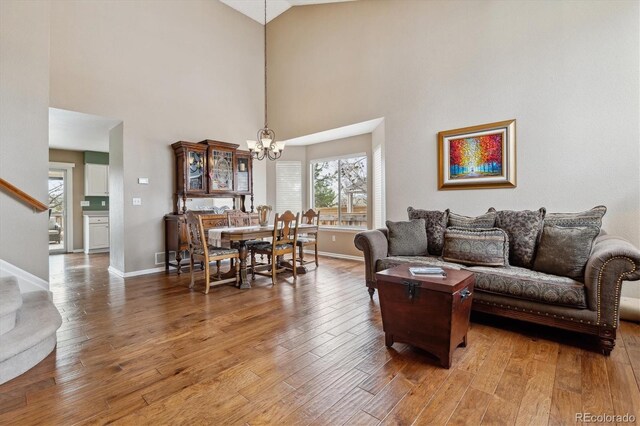 living room with baseboards, stairs, wood finished floors, and a notable chandelier