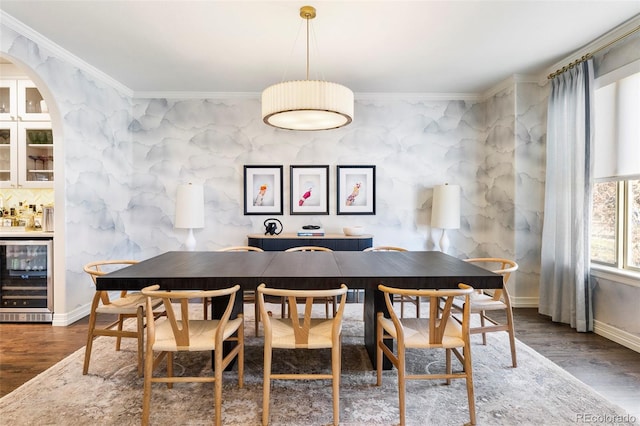 dining room with bar area, hardwood / wood-style flooring, beverage cooler, and crown molding