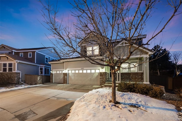 view of front of home featuring driveway, an attached garage, fence, and brick siding