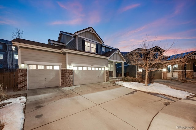 craftsman house featuring driveway, a garage, fence, board and batten siding, and brick siding