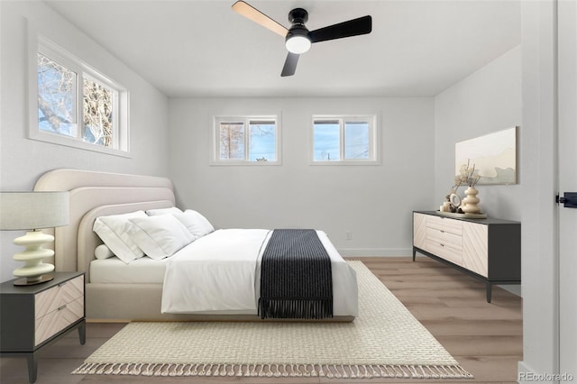 bedroom with multiple windows, ceiling fan, and wood-type flooring