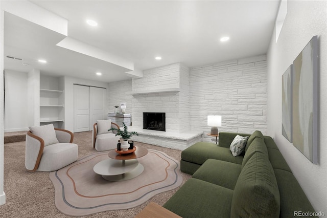 living room featuring carpet floors, built in features, and a stone fireplace