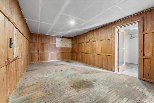 empty room with wood walls and light hardwood / wood-style flooring