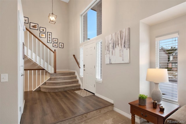 entrance foyer featuring a towering ceiling and wood-type flooring