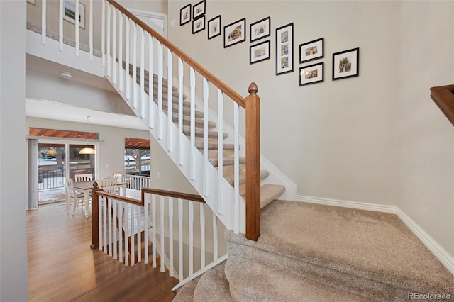 staircase with a towering ceiling and hardwood / wood-style flooring