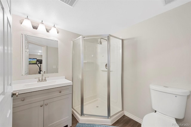 bathroom with an enclosed shower, vanity, wood-type flooring, and toilet