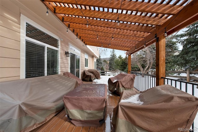 snow covered deck with area for grilling and a pergola