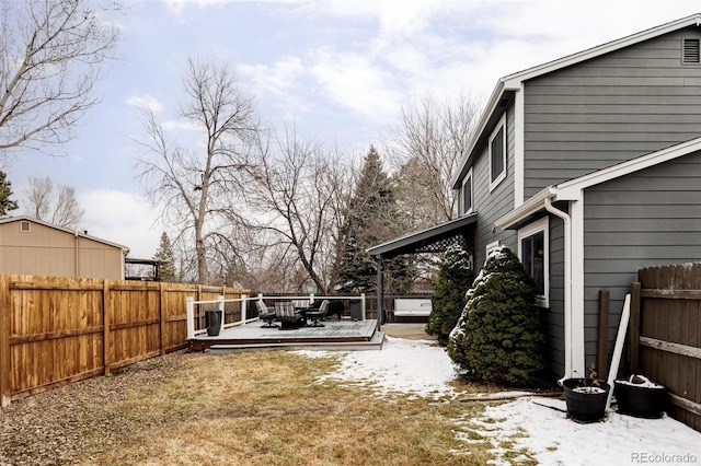 yard covered in snow with a fenced backyard and a deck