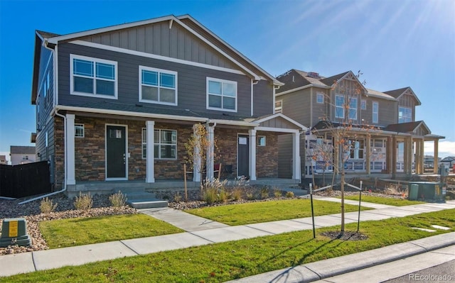 18726 E 99th Ave, Commerce City, CO 80022 - craftsman house featuring covered porch, a front yard, and stone siding