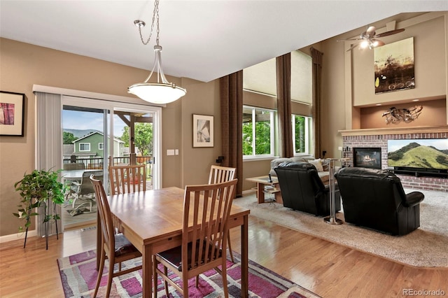 15962 W 70th Dr, Arvada, CO 80007 - dining space featuring light wood finished floors, a brick fireplace, and ceiling fan