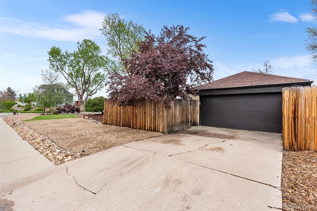 view of home's exterior with fence, a shingled roof, and a garage