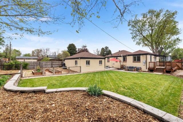 back of property with a garden, a deck, an outdoor living space, a patio, and stucco siding