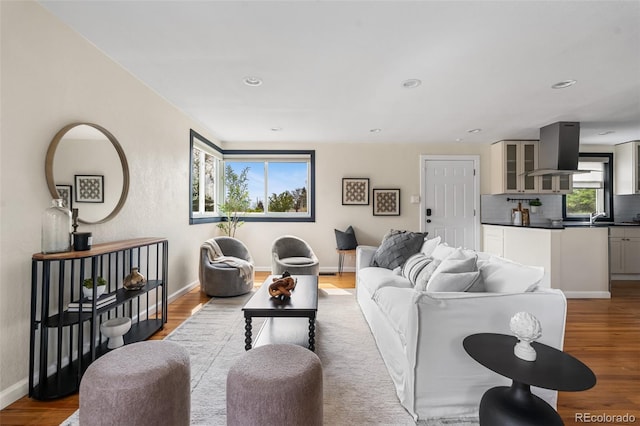 living room with healthy amount of natural light, wood finished floors, baseboards, and recessed lighting