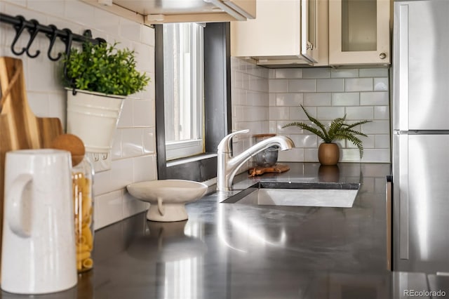 interior space featuring freestanding refrigerator, tasteful backsplash, and a sink